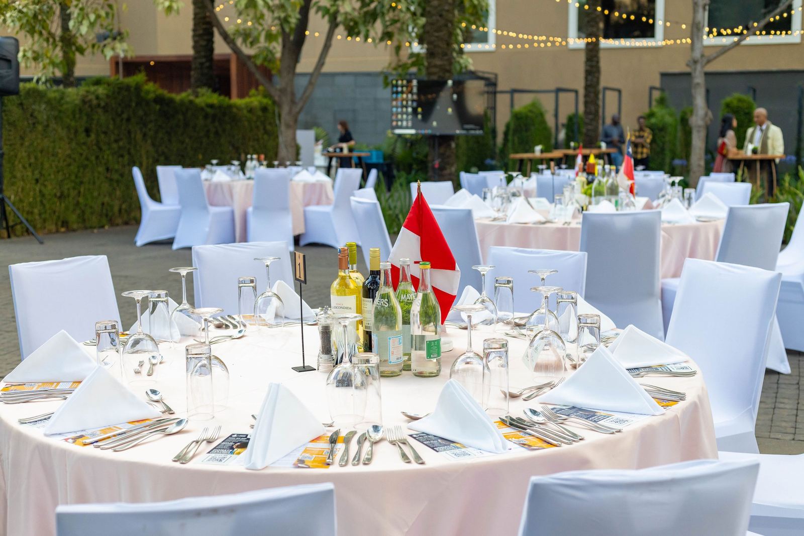 Round tables set for dinner in the garden at dusk