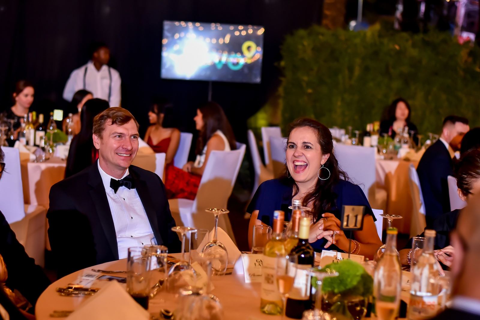 Guests in black tie laughing at their table