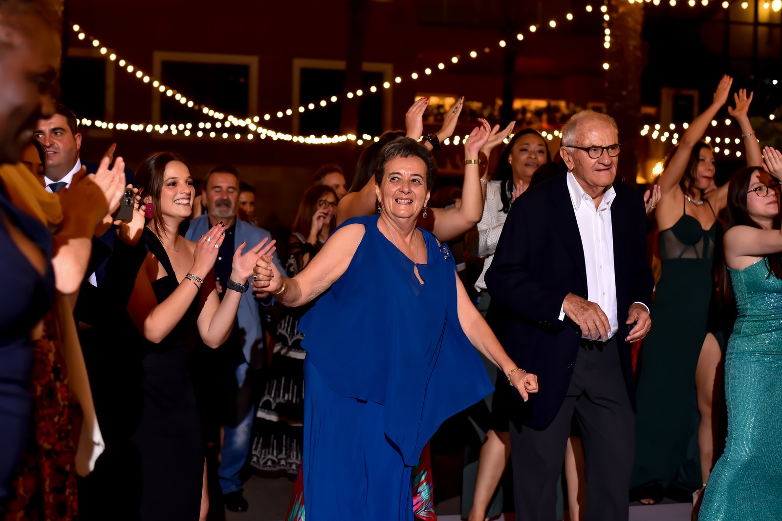 Guests of every generation dancing under string lights